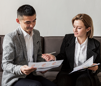 Two professionals discussing financial reports during a corporate planning meeting